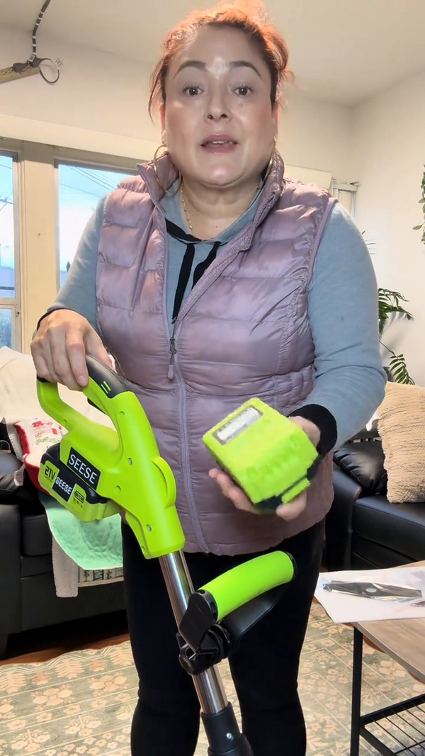Mujer mostrando la podadora inalámbrica con su batería recargable