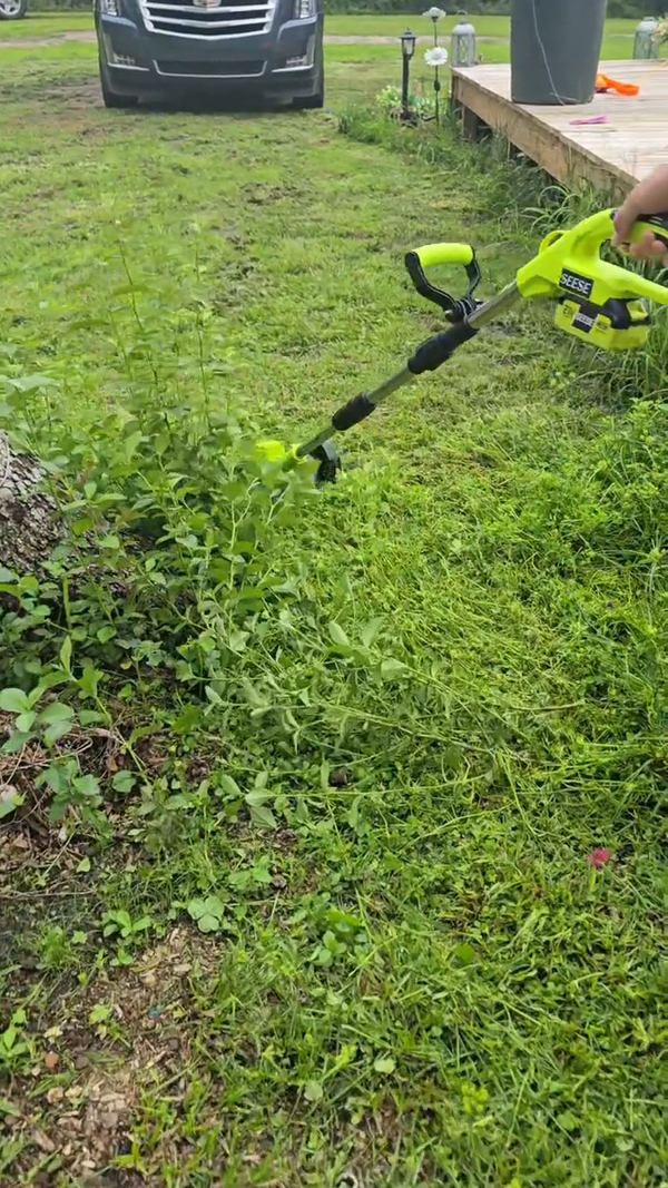 Podadora inalámbrica cortando orillas y maleza cerca de la entrada del patio