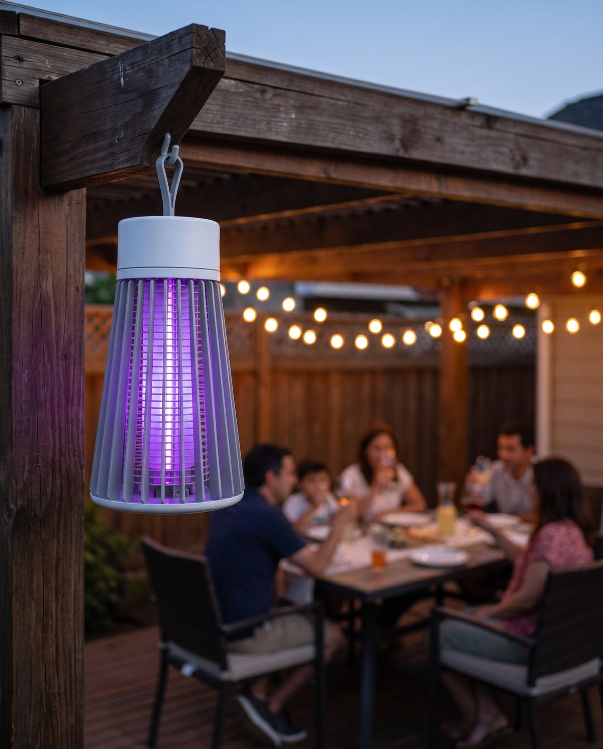 Lampara mata mosquitos colgada en el patio mientras la familia cena